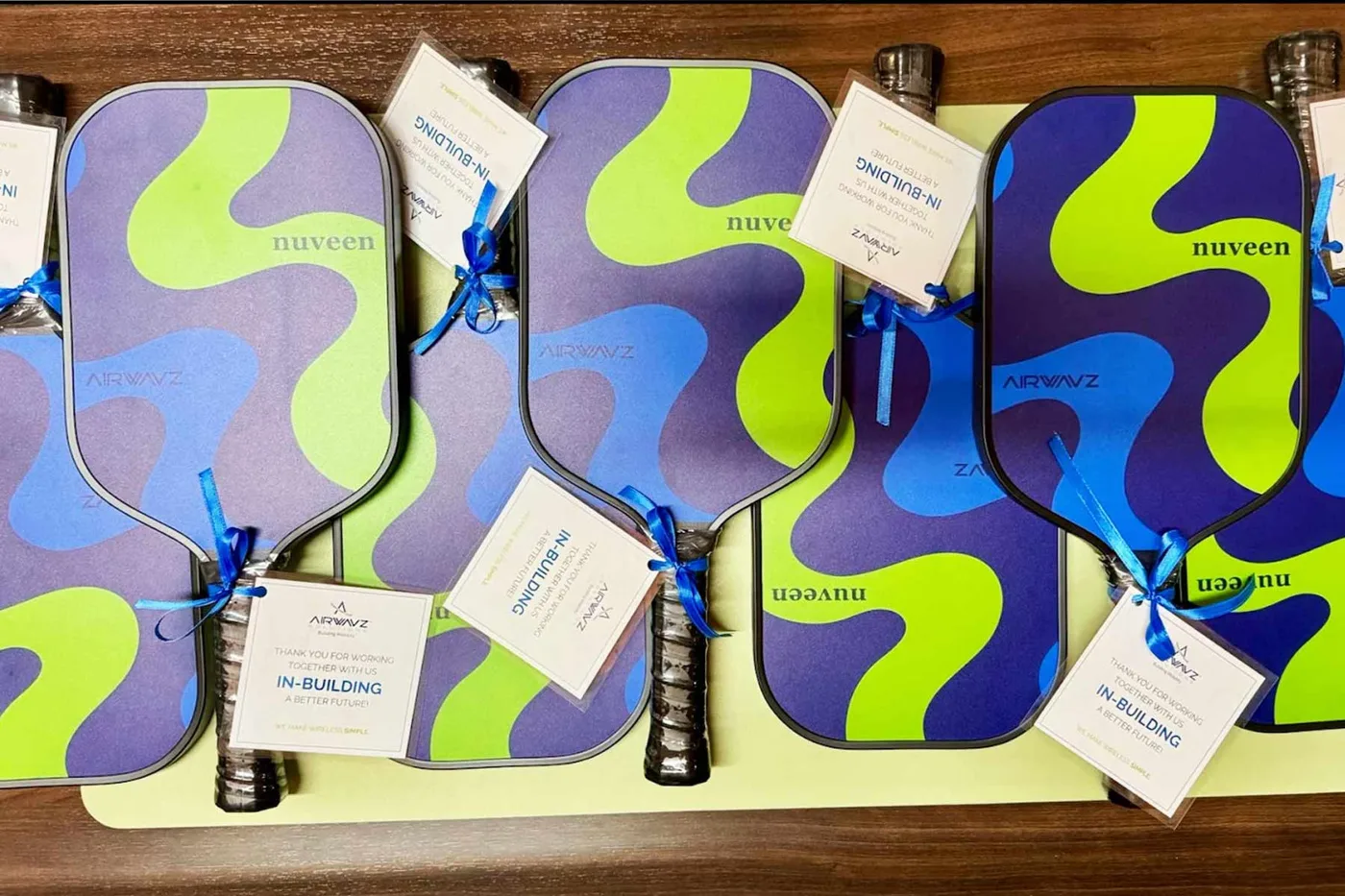 Custom-printed pickleball paddles lined up with gift tags